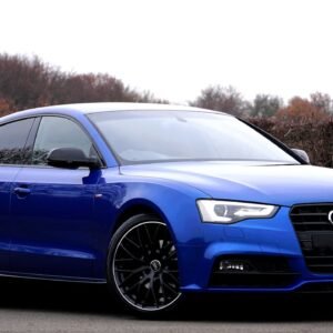 Elegant blue luxury car parked outdoors against a natural backdrop.